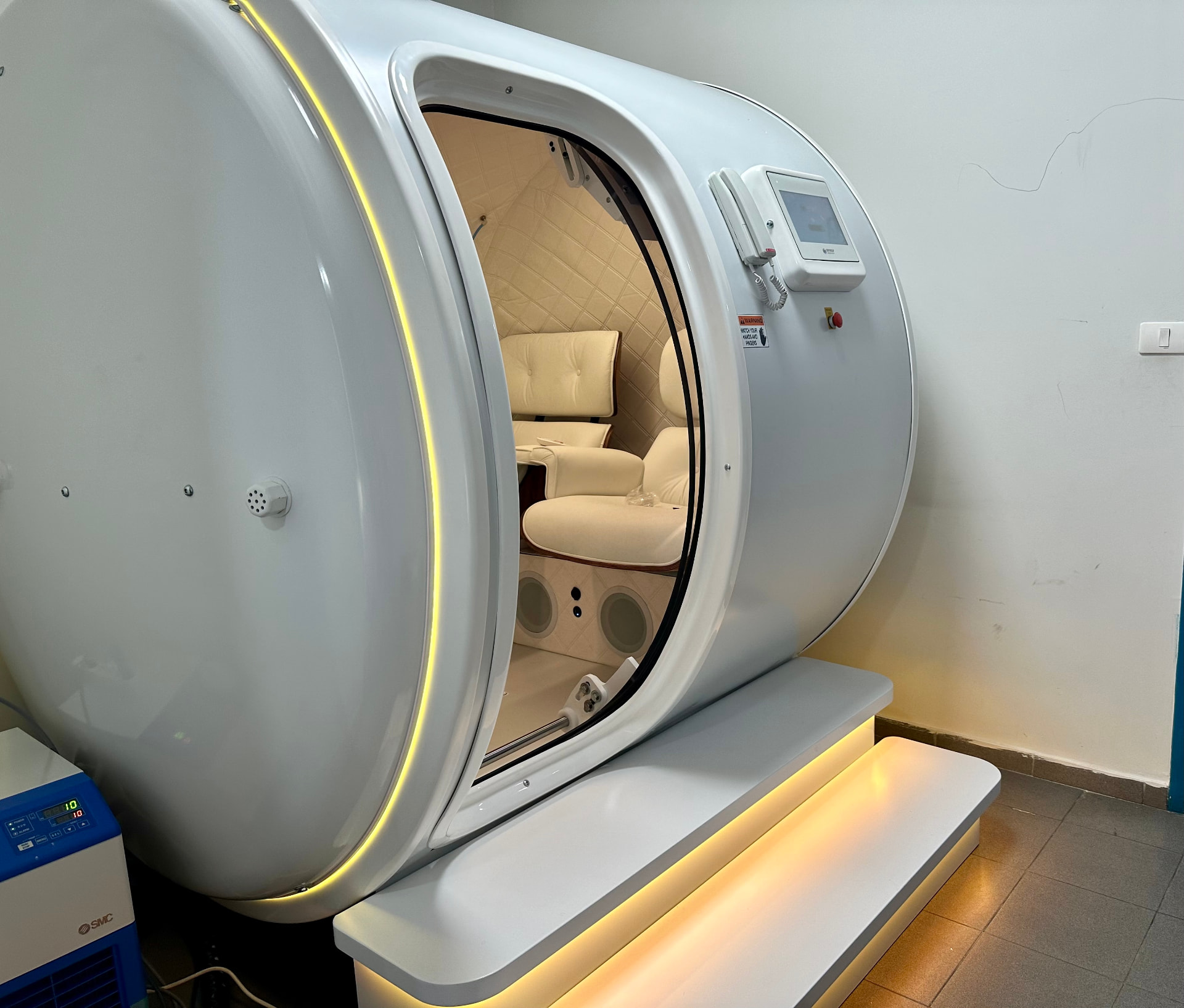 Open door of the hyperbaric chamber showing the cushioned treatment seats